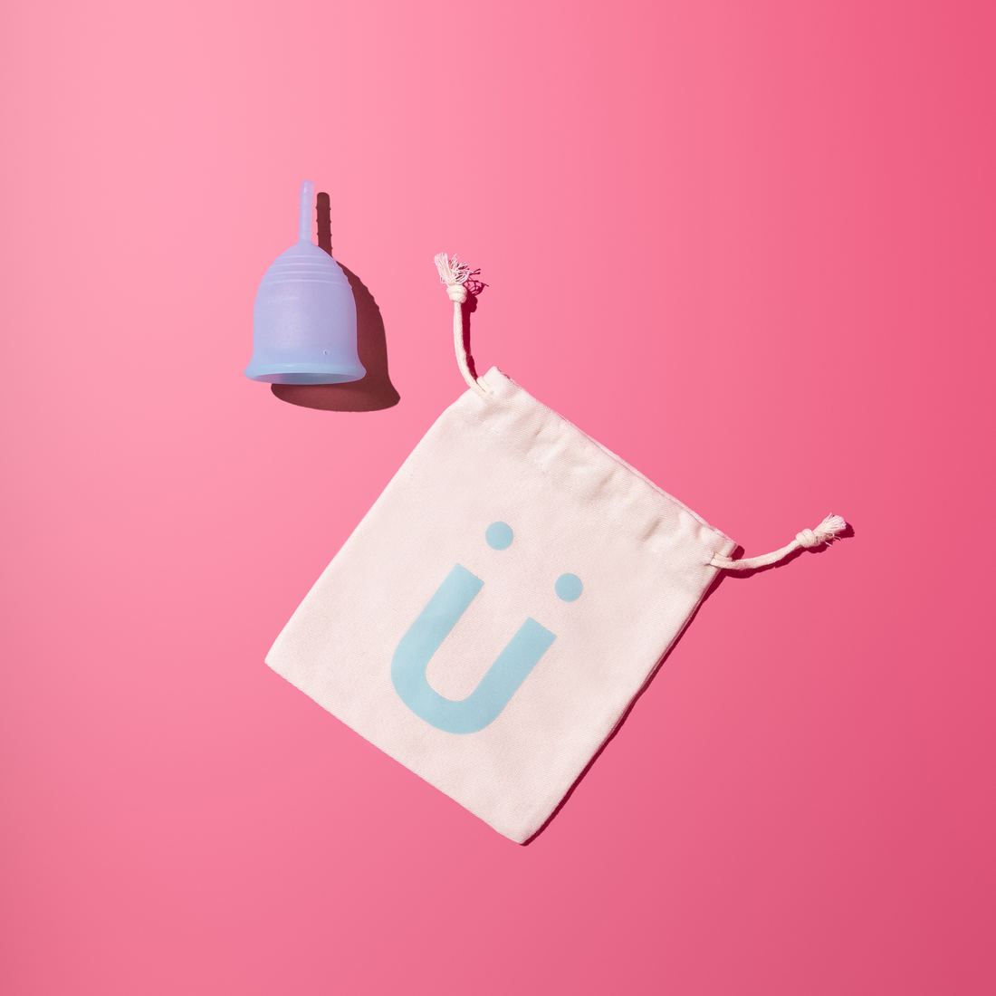Menstrual cup with a branded pouch on a pink background