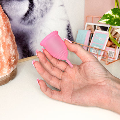 Hand holding a pink Menstrual Cup with handle