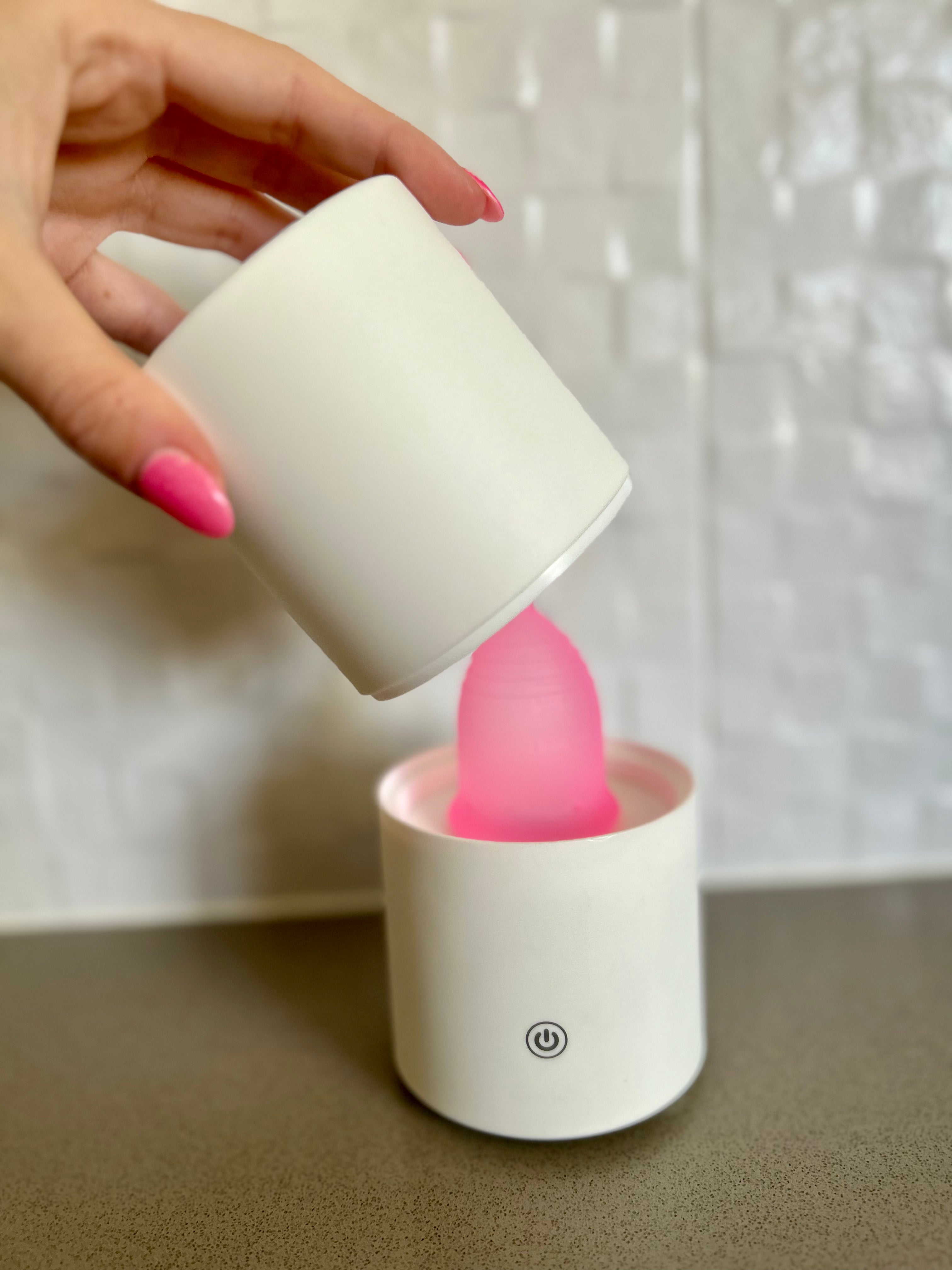 A person holding a pink steam steriliser inside a white container